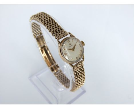 A vintage Omega ladies 9ct gold wristwatch with 9ct gold bark effect bracelet.  The white enamel face with baton numerals 29g