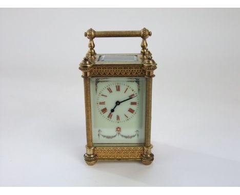 A late 19th century brass carriage clock, the casework with filigree and other detail enclosing a painted dial, the red numer