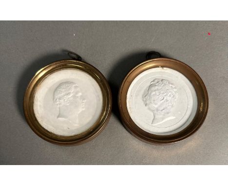 A pair of framed plaster portrait medallions.
