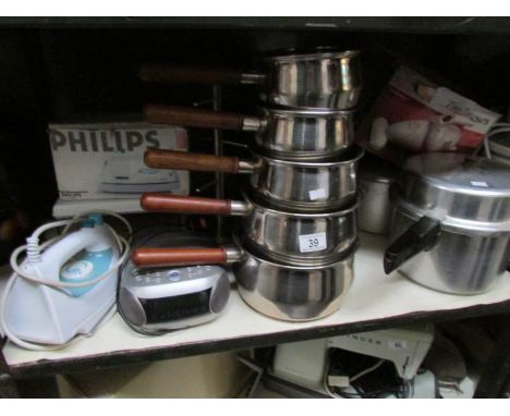 A shelf of kitchen ware including stainless steel pans
