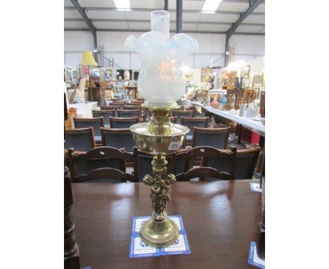 A brass cherub based oil lamp with vaseline glass shade