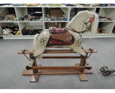 A reproduction wooden Rocking Horse having real horse hair mane and tail, leather saddle, no stirrups, on traditional swing a