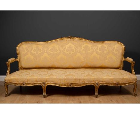 A large French giltwood sofa, the shaped back with floral carved ornament to the cresting rail, with open arms, serpentine fr