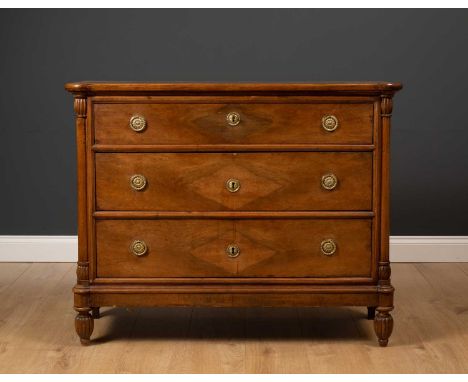 A late 19th or early 20th century French walnut three drawer commode, with outset pilaster columns to the front corners and o