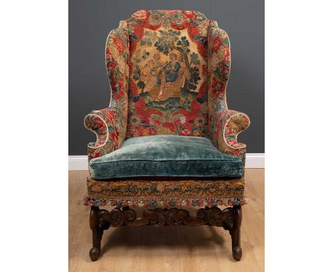 A James II walnut wing armchair with an eared back and outstretched scrolling arms, covered in associated 18th century gros-p