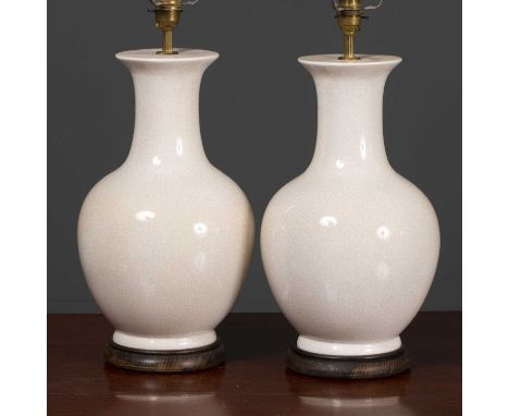 A pair of cream crackle glaze ceramic table lamps with turned wooden socles, 46cm high to the light fitting (2)Condition repo