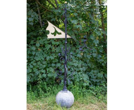An early 20th century black painted wrought iron weathervane with pierced gilt flag vane and on a lead covered wooden sphere,