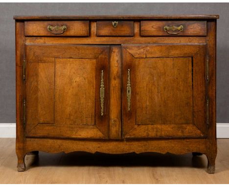 An early 19th century French oak and walnut side cabinet with three drawers above two doors, with brass handles and brass esc