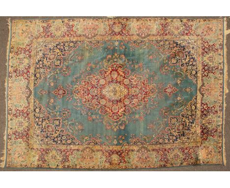 An old Kirman light blue ground carpet with central diamond motif, further decorated with flowers within a floral border, 394