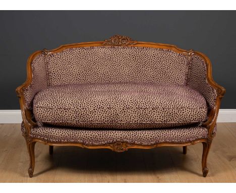 An 18th century French style walnut small sofa with purple spot upholstery and carved decoration to the frame, 128cm wide x a