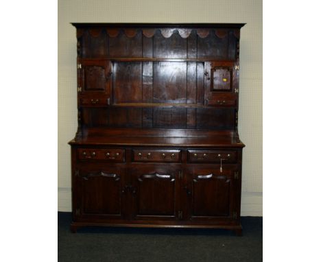 A 18th century-style oak tall dresser, the rack with moulded cornice and shaped frieze over two shelves flanked by fielded pa