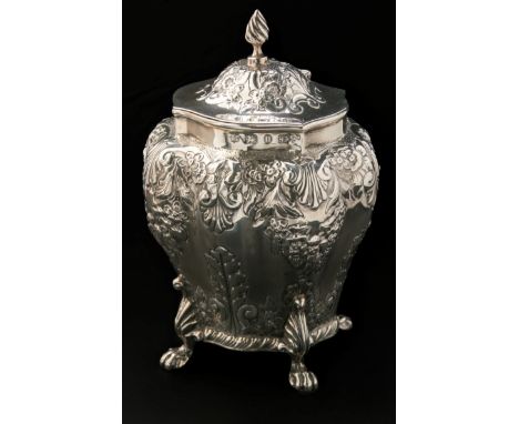 A Victorian tea caddy, lobed inverted pear-shape, with paw feet, the sides and hinged cover profusely chased with scrolling f