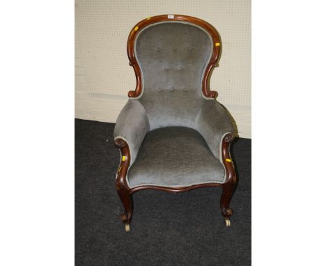 A Victorian walnut framed button upholstered spoon back armchair with scroll carved arms, overstuffed serpentine seat, on cab