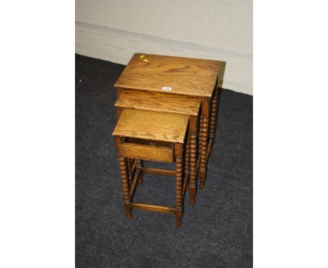 A 1920s oak nest of three occasional tables will bobbin turned supports, 42cm wide