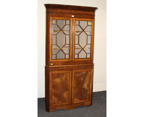 A 19th century mahogany floor standing corner cupboard, the moulded cornice over a pair of astragal glazed doors enclosing tw