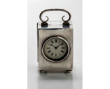 A small silver mounted carriage clock, the engine-turned cased with hinged carrying handle, on four ball feet, white enamel d