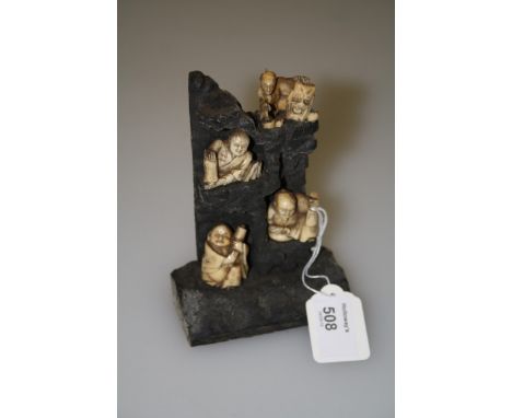 A collection of four Japanese Meiji period ivory netsuke, each fashioned a seated individual with oni mask mounted on a hardw