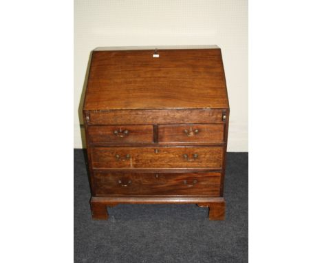 A George III mahogany estate bureau, the wide fall with moulded edge enclosing a fitted interior over two short and two long 