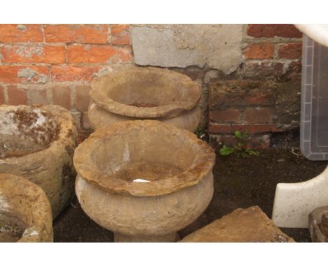 A pair of old turned sandstone goblet form urns, with everted rims, 38cm diameter, together with a shallow miniature stone tr