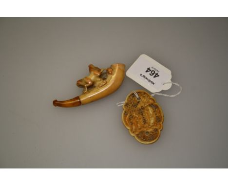 A 19th century carved ivory belt toggle depicting figures in a landscape against a trellis back ground, together with a lady'