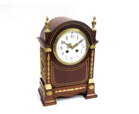 A late 19th/early 20th Century walnut and gilt brass mounted French mantel clock of arched form, enamelled Arabic convex dial