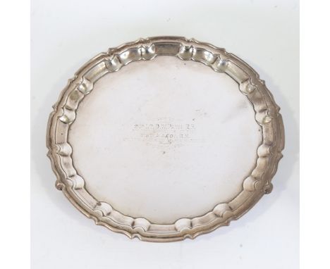 A George V silver salver, circular form with scalloped rim raised on three acanthus leaf feet, with military presentation ins