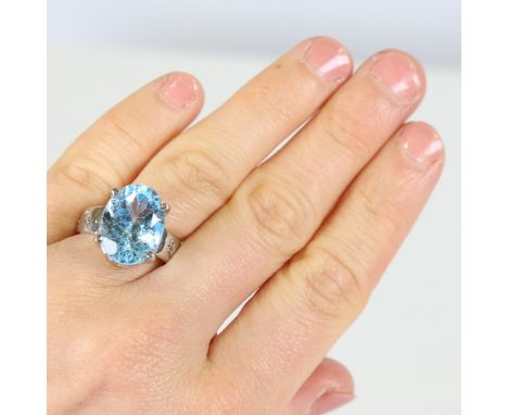 A modern Continental silver blue topaz dress ring, set with 10ct oval mixed cut topaz and round brilliant cut diamond shoulde