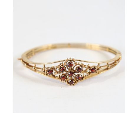 A late 20th century 9ct gold garnet hinged bangle / bracelet, openwork bead-edge flowerhead settings with round-cut garnets, 