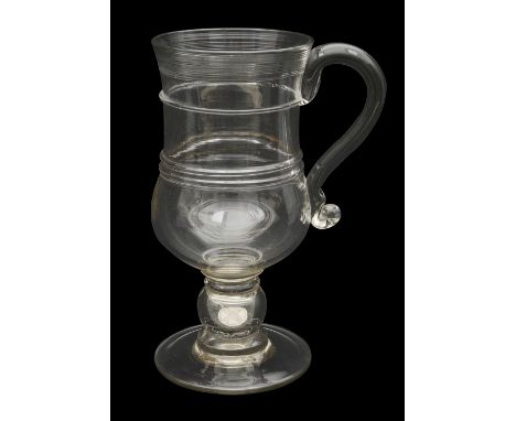 A large 19th century glass coin tankardof bell form with a thread spun rim and applied scroll handle, the stem with a hollow 