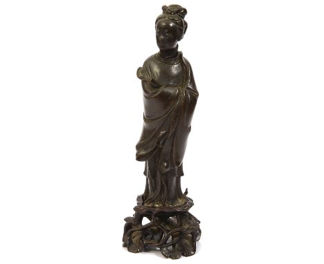 A Chinese bronze figure of Guanyin late 18th/early 19th century, modelled wearing long flowing robes, holding a scroll, on a 