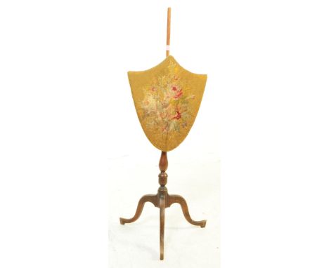 A early 19th Century Victorian ladies face firescreen of armorial form with floral spray design. On mahogany column raised on