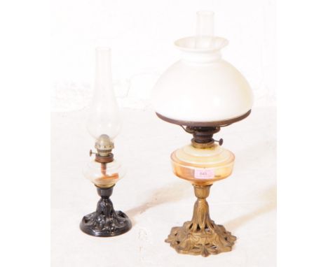 Two late Victorian oil lamps; both with cast iron Nouveau style bases, one painted black the other bronze; clear glass reserv