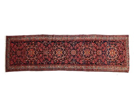 Malayir Runner West Iran, circa 1920 The indigo field of floral vines around a column of flowerhead medallions enclosed by tr
