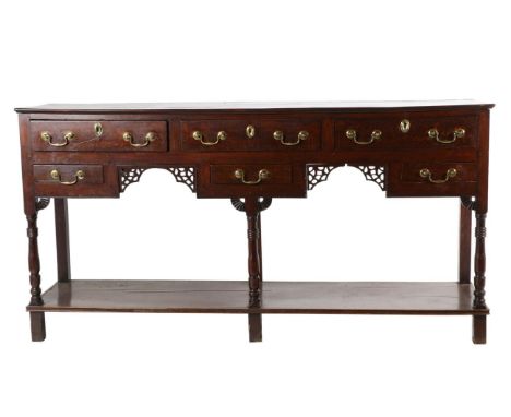 A George III Oak Open Dresser, mid 18th century, with an arrangement of six drawers above a fret carved arched apron, on balu