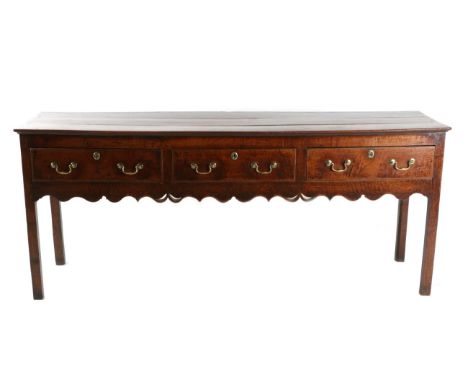 A George III Oak Dresser, 3rd quarter 18th century, with three frieze drawers above a wavy shaped apron, on square chamfered 