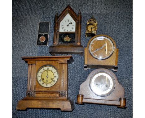 Four wooden and one brass mantle clock.
