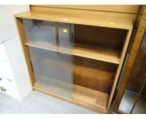 A neat light oak sliding glass door low bookcase