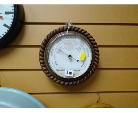 A vintage circular carved oak rope patterned surround barometer/thermometer made in London