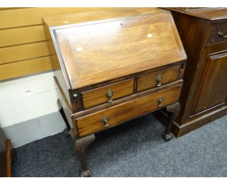 A vintage oak bureau with two short above one long drawers standing on ball & claw feet