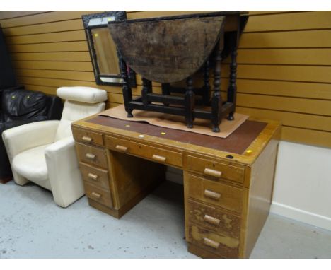 A vintage light oak kneehole desk with four banks of drawers to either side of a central drawer and leather effect insert top