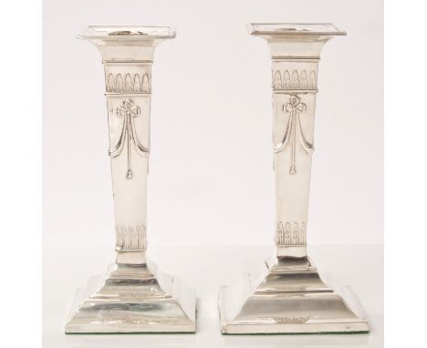 Pair early George V silver neoclassical-style candlesticks of tapering form, with raised bow and swag decoration, on stepped 