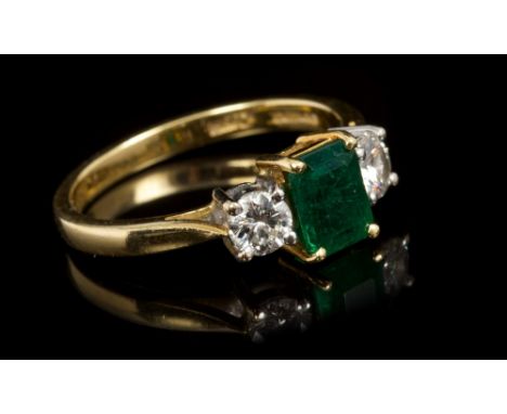 Emerald and diamond three stone ring, the central rectangular step cut emerald calculated to weigh approximately 0.77 carats,