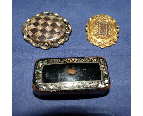 Two Victorian brooches set with plaited hair in ornate gilt metal frames; a 19th century papier mâché snuff box with abalone