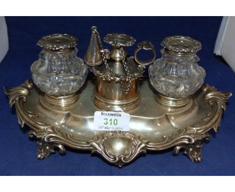 An oval rococo standish with relief acanthus decoration and scroll feet, 2 glass bottles and central dwarf chamber stick with