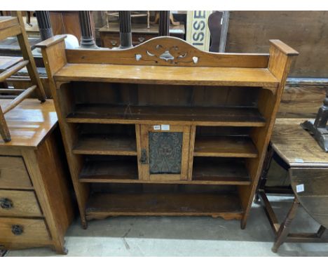 An Art Nouveau oak open bookcase, fitted with a central cupboard, the door inset with a hammered copper panel, width 106cm, d