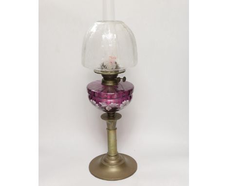 A Victorian oil lamp with an amethyst floral enamelled glass bowl and clear etched shade, 65cm high