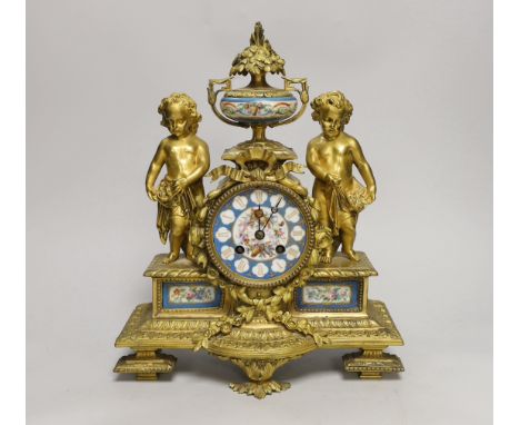 A French decorative ormolu putti mantel clock with porcelain clock face, side panels and urn