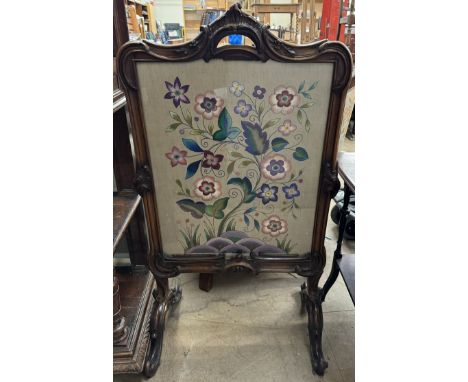 A 19th century walnut framed fire screen with a leaf moulded scrolling handle to the top, the rectangular panel, decorated wi