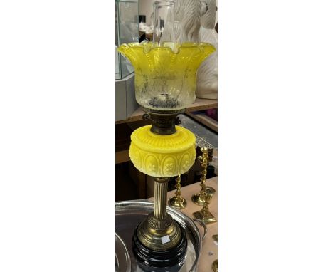 A Victorian oil lamp with a brass column and lemon yellow glass reservoir and graded glass shade