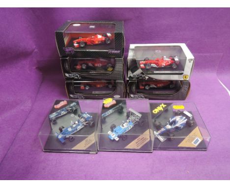 Five Hotwheels 1:43 scale diecast Ferrari F1 cars, two Quartzo and one Onyx similar diecasts, all in plastic display cases